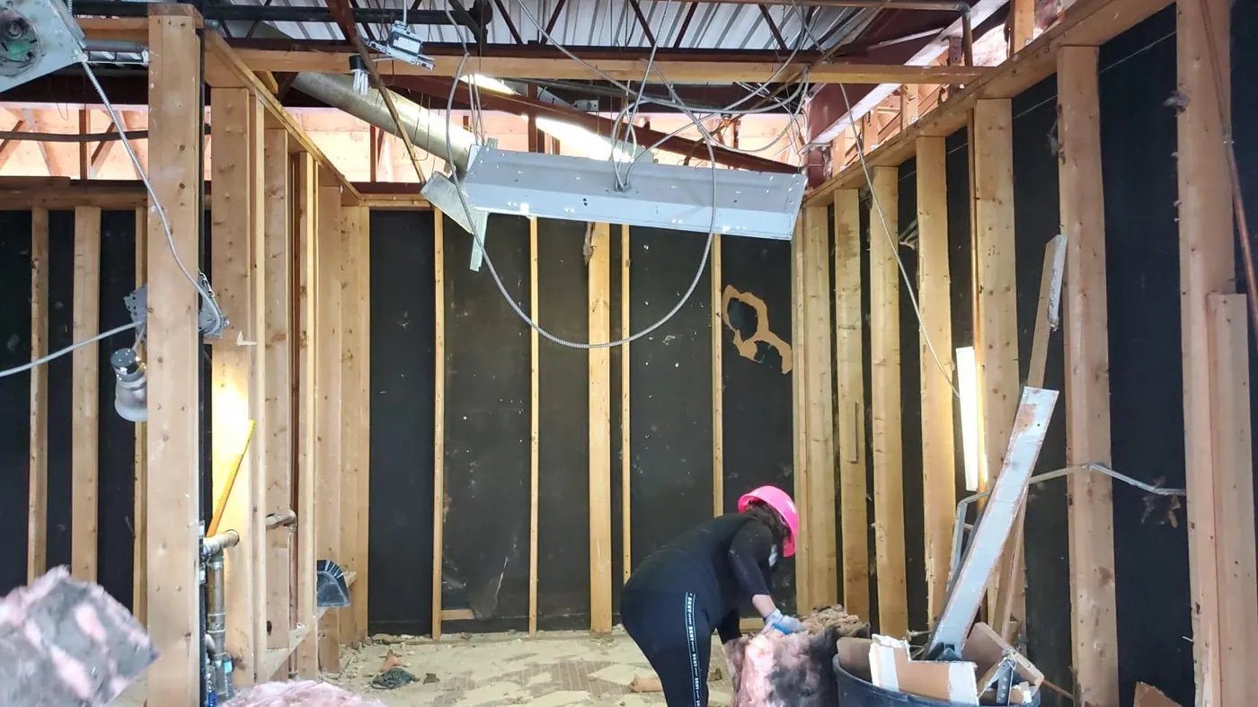 A woman in a pink hard hat working inside a construction renovation