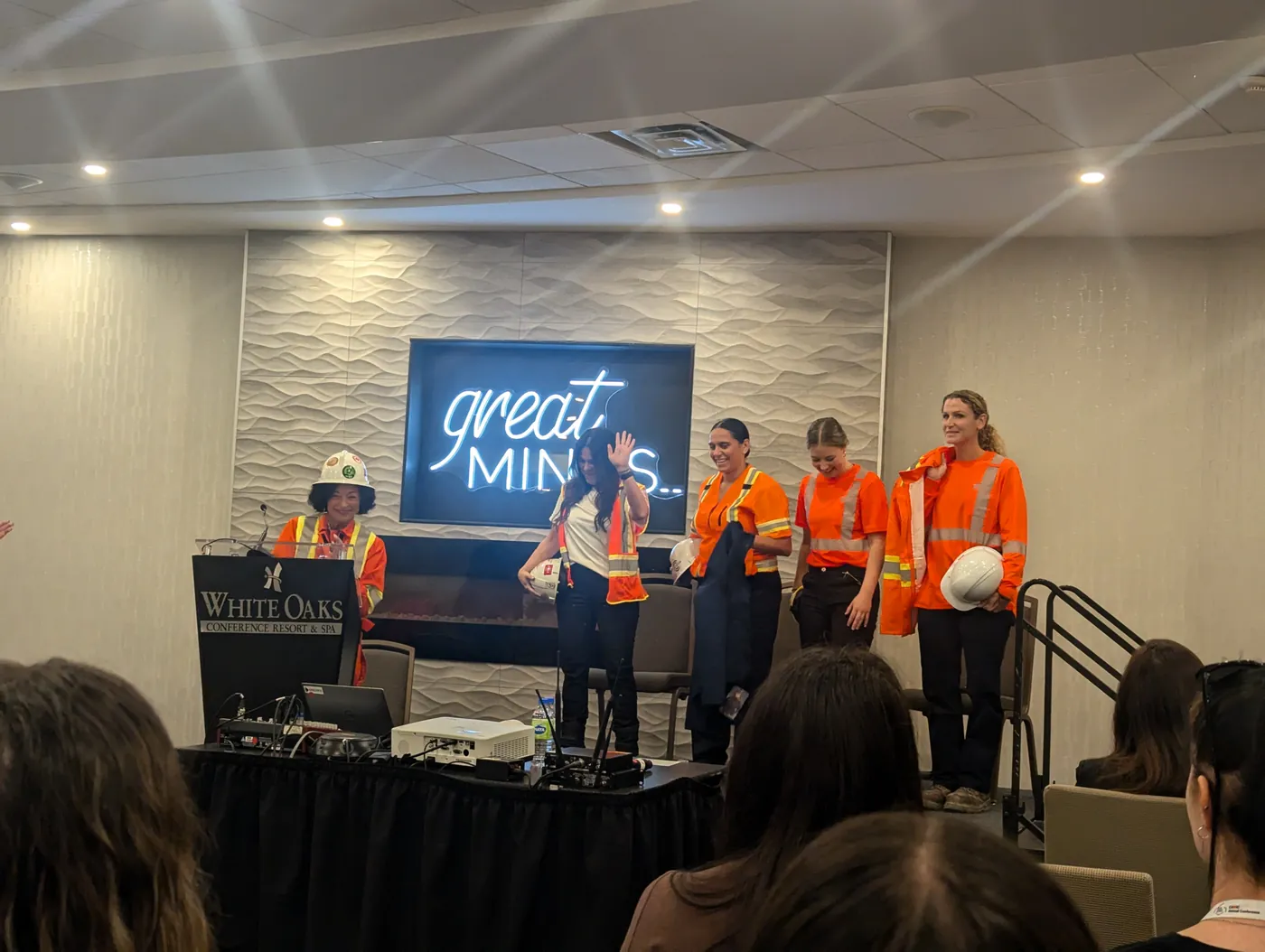 Women in safety gear gathered on a conference stage